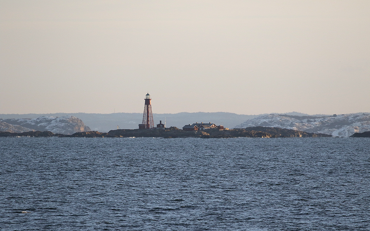Pater Noster fyr på en kobbe i havet med snöiga berg bakom